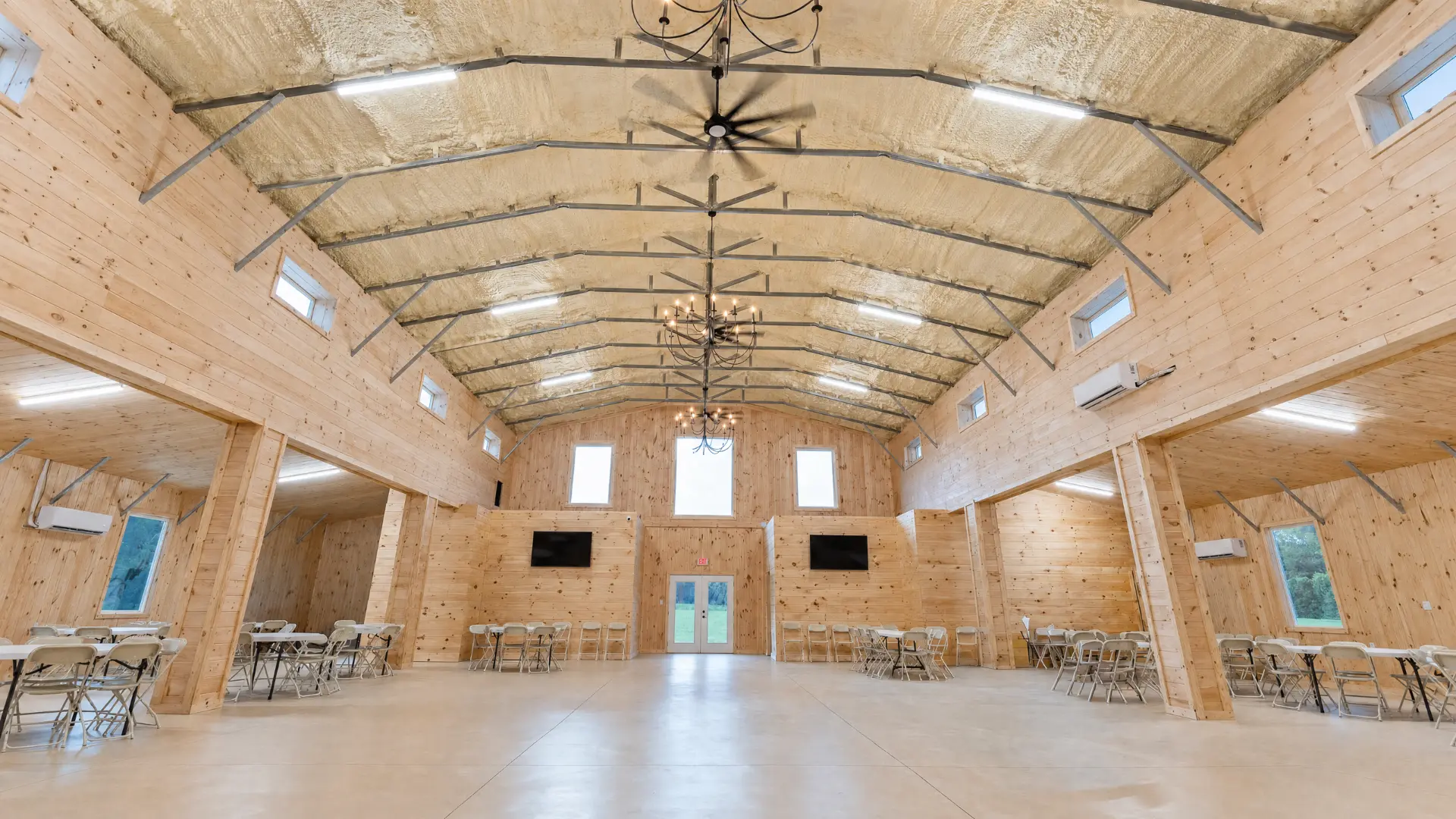 Vaulted barn hall with chandeliers and open dance floor