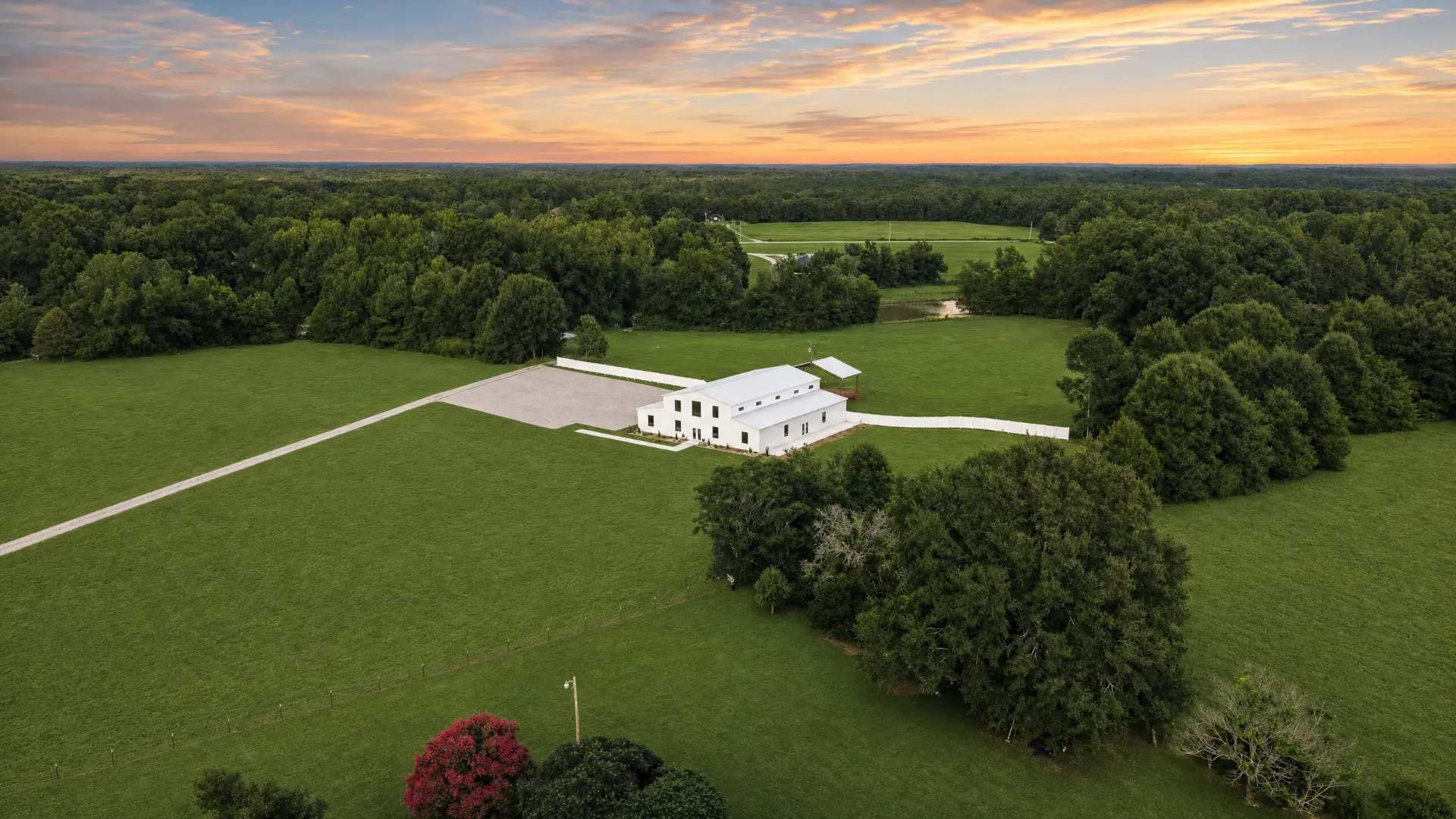 Aerial view of the white barn and grounds at golden sunset