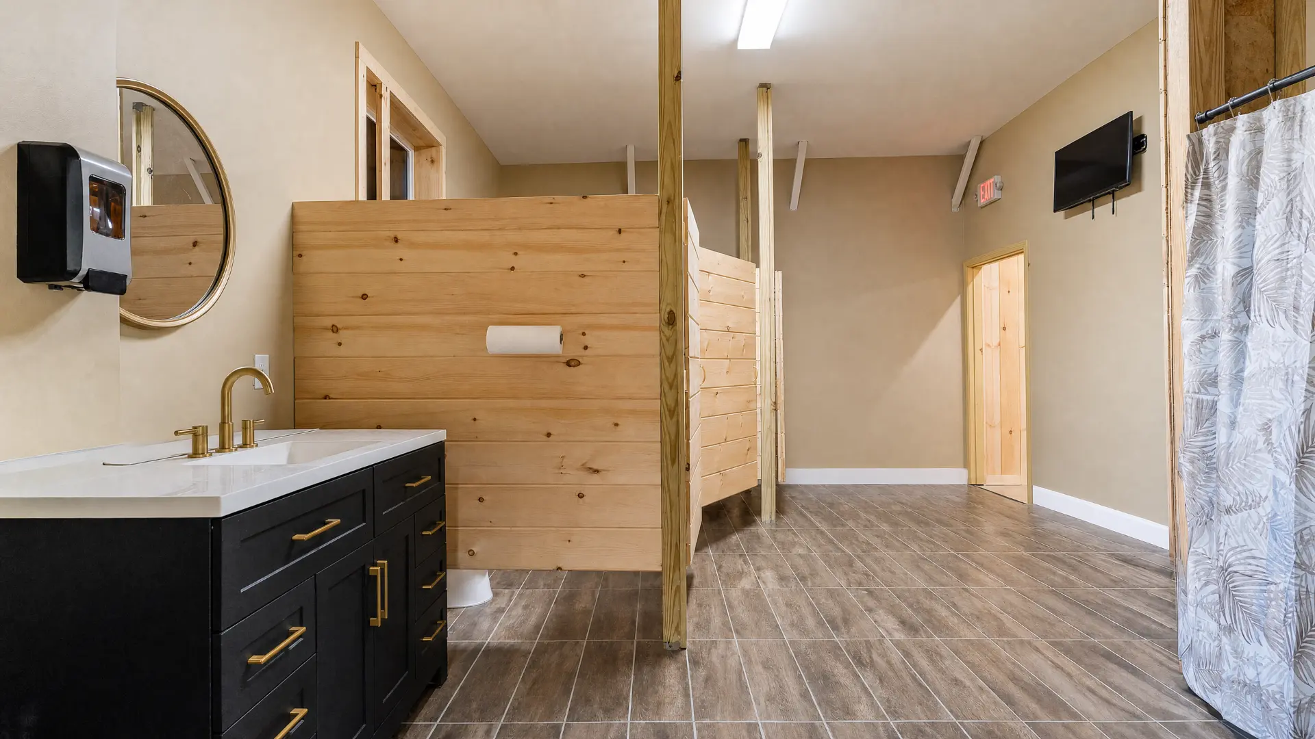 Restroom with black vanity, gold fixtures and pine partitions